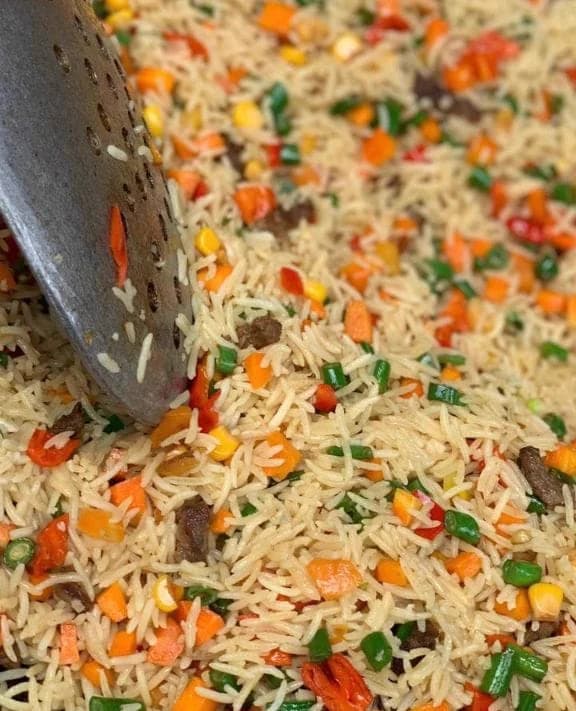 A close view of Dlawz coconut rice with mixed vegetables being turned with a serving spoon